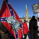 A supporter carries a US Confederate flag during the Freedom Convoy protesting Covid-19 vaccine mandates and restrictions in front of Parliament on January 29, 2022 in Ottawa, Canada. - Hundreds of truckers drove their giant rigs into the Canadian capital Ottawa on Saturday as part of a self-titled “Freedom Convoy” to protest vaccine mandates required to cross the US border.